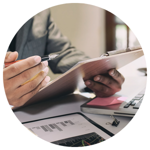 hands holding a clipboard next to a laptop