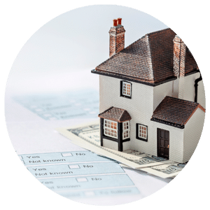 small model house sitting on top of paper money and financial forms